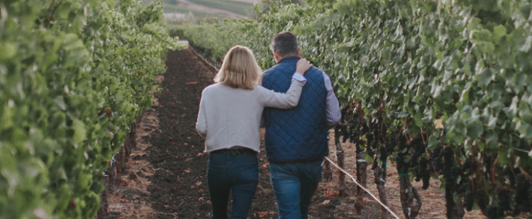 Sean and Nicole Minor walking through a vineyard