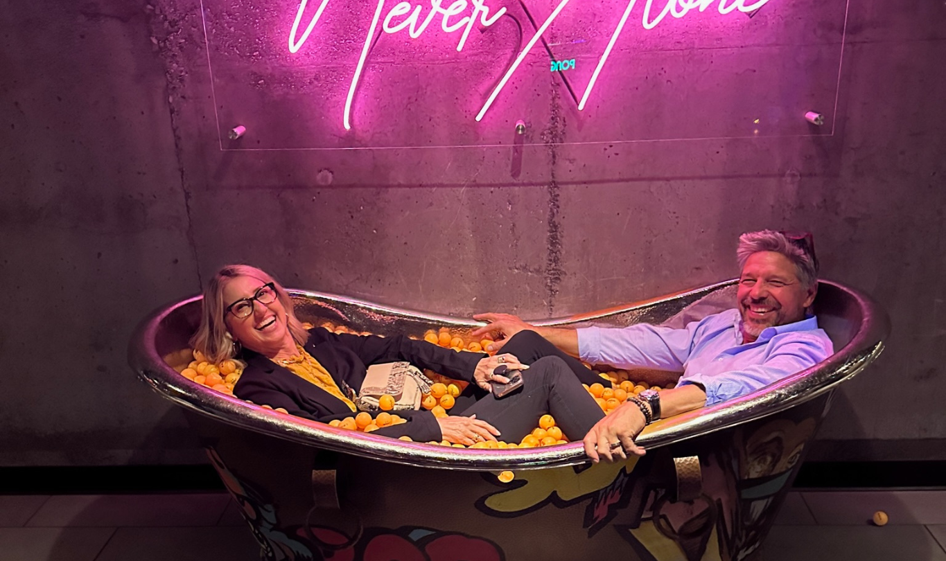 Sean and Nicole in a bathtub of corks under a neon sign