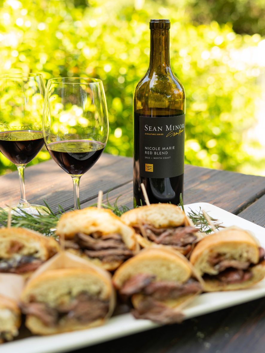 platter of steak sandwiches with bottle of nicole marie with wine glasses