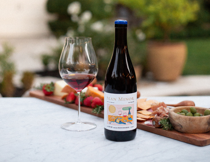 bottle and glass of wine by charcuterie board